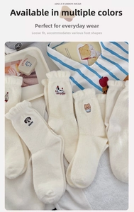 Detail of cream white socks featuring cute animal embroidery and wavy ruffled edges
