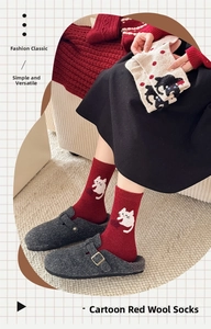 Close-up of red wool socks featuring cute white cartoon cat patterns for winter warmth