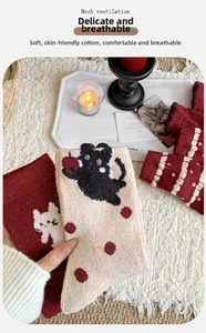 Detailed knit of red and beige wool socks with cute cat patterns on a plush white rug