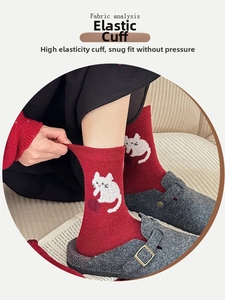 Detailed view of elastic ribbed cuff on red wool blend socks with cute cat pattern