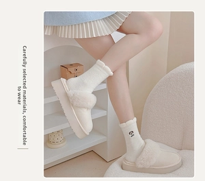 Close-up of fluffy cream plush slippers with cute dog embroidery socks for winter comfort