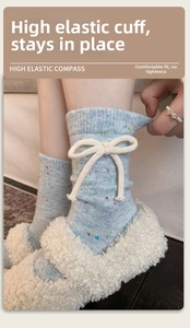 Close-up of light blue speckled wool socks with a white knitted bow and elastic cuff