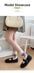 Close-up of beige knit socks with bear pattern and grey Mary Jane shoes on wood floor
