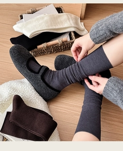 Close-up of ribbed cashmere mid-calf socks in various colors on wooden floor