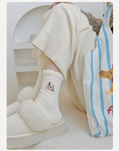 Detail of warm white plush sock with cute puppy embroidery and wavy lace cuffs