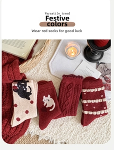 Detail of wool blend socks with red cat patterns and festive argyle knit textures