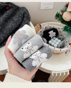 Gros plan de chaussettes en laine avec motifs d'ours et nœuds dans un décor d'hiver
