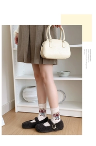 Detailed view of beige wool socks with cartoon bear pattern and brown Mary Jane shoes
