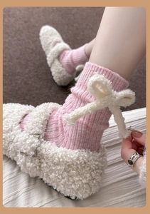 Macro shot of pink knit socks featuring plush white bow details and bouclé Mary Jane shoes