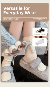 Close-up of cream wool blend socks with blue bows and stylish indoor felt shoes