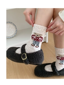 Detail of cute embroidered bear on cream knitted wool socks with colorful dots