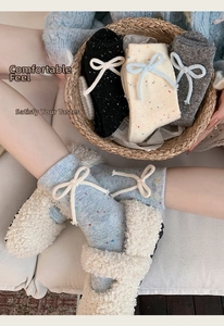 Detail of speckled wool socks with side bow ribbons and cozy knit texture in soft light