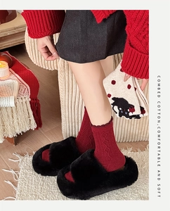Detail of red combed cotton socks with diamond knit pattern and black plush slippers