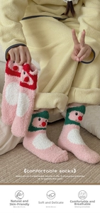 Detail von rosa Korallenvlies-Thermosocken mit roten 3D-Bommeln und Rentiergesicht