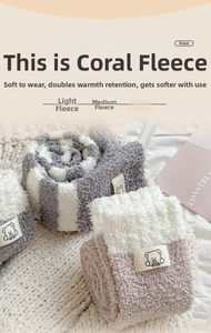 Close-up of thick coral fleece warm socks with cute bear patch and striped texture