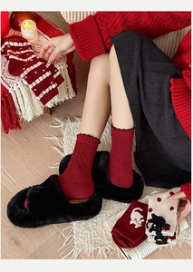 Cozy red argyle wool socks with ruffle trim paired with black fuzzy slippers on wooden floor