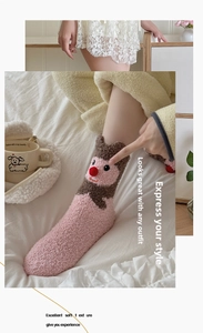 Detail von rosa Korallenvlies-Socken mit süßem 3D-Tiergesicht und roter Pompon-Verzierung