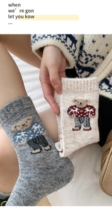 Close-up of thick knitted wool socks featuring a cute bear pattern and colorful marl yarn