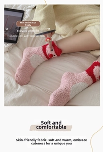Nahaufnahme der rosa Korallenfleece-Socken mit süßem Cartoon-Motiv und Bommel-Detail
