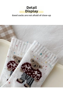Close-up of white wool socks featuring colorful speckle yarn and a cute bear pattern