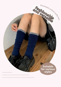 Detail of navy blue wool calf socks with gray ribbed edges paired with black leather shoes