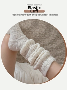 Close-up of elastic ribbed cuff on white wool knit leg warmer with colorful speckles