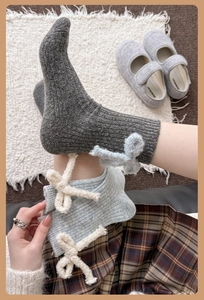 Detail of wool socks featuring vertical knit texture and plush bow accent on the side