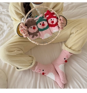 Nahaufnahme von warmen Korallenvlies-Socken mit niedlichen Rentier-Mustern und Pompons