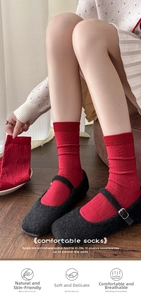 Detail of red crew socks with floral embroidery and vertical stripes worn with black shoes