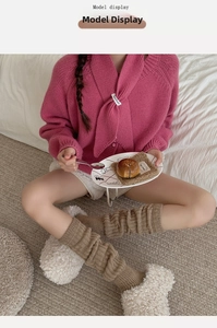 Close-up of stylish khaki knit leg warmers paired with white plush fleece slippers