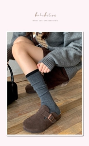 Detail of dark grey ribbed wool socks paired with brown suede buckled mule shoes