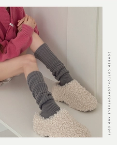 Close-up of gray knit leg warmers showing thick vertical rib texture and combed cotton fabric