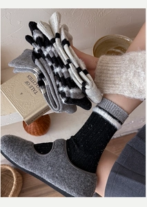 Close-up of thick striped wool socks with textured knit details and warm felt shoes