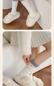 Close-up of cozy coral fleece socks with bear patch and plush slippers on wooden floor