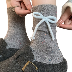 Thick grey wool socks with colorful flecks and a large blue knit bow accent