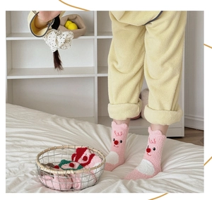 Detail von rosa Korallenvlies-Socken mit süßen Tierohren und kleinen roten Plüschbällen