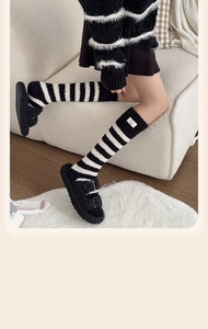 Detail of coral fleece striped calf socks with cute bear patch in home setting