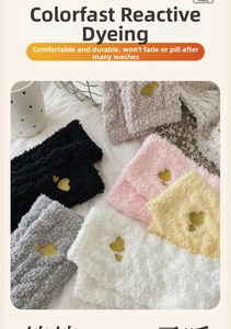 Close-up of heart embroidery on plush coral fleece socks in soft neutral tones