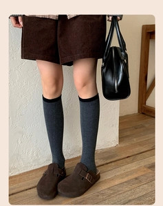 Detail of dark grey wool blend calf socks with black trim paired with suede mules