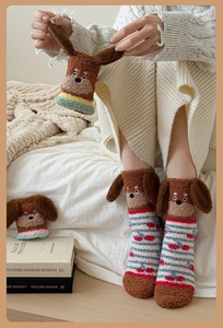 Detailed close-up of 3D cartoon dog plush ears on warm coral fleece winter socks