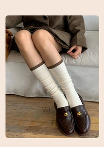 Detail of wool-blend mid-calf socks with contrast trim and vintage leather shoes