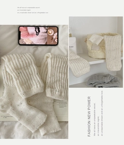 Close-up of cream wool knit leg warmers with colorful specks and vertical ribbed texture