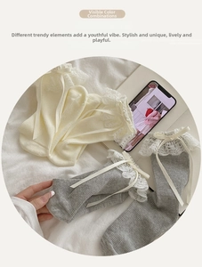 Dettaglio di calze Lolita con bordo in pizzo e fiocco di seta nei colori bianco e grigio