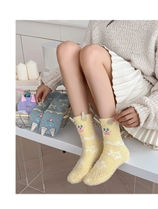 Gros plan de chaussettes en polaire corail jaune avec cornes de monstre et broderie mignonne