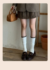 Detail of wool calf socks paired with brown leather loafers and a pleated skirt