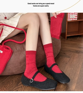 Close-up of red knit mid-calf socks with cute 3D bear and heart patterns on models legs