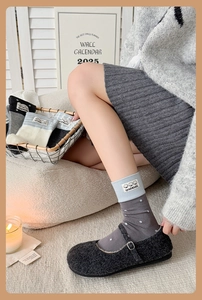 Detail of grey polka dot cotton socks with handmade label and dark grey wool Mary Janes