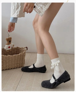 Détail de chaussettes blanches à nœud en dentelle portées avec des chaussures Mary Jane