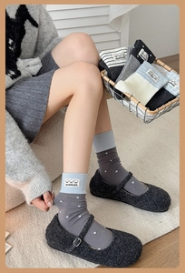 Close-up of grey polka dot cotton socks with blue ribbed cuffs and handmade cloth label