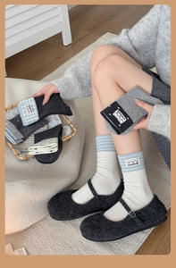 Detail view of cotton crew socks featuring cute cartoon cloth tags and ribbed knit texture